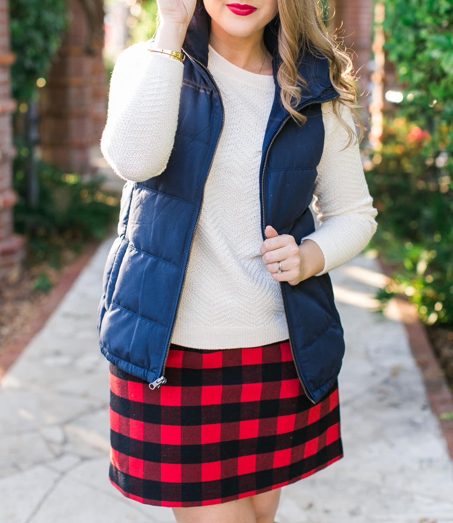 A cozy fall outfit + the best Gap and Old Navy Black Friday Deals + get $20 back with any $50 purchase at Gap Inc with your Marriott Rewards Premier Card. Preppy fall outfit idea featuring Old Navy navy puffer vest, cream sweater, red plaid skirt, Tory Burch boots, Foster Grant sunglasses, and Clinique Cherry Pop lipstick styled by Florida fashion blogger Ashley Brooke Nicholas