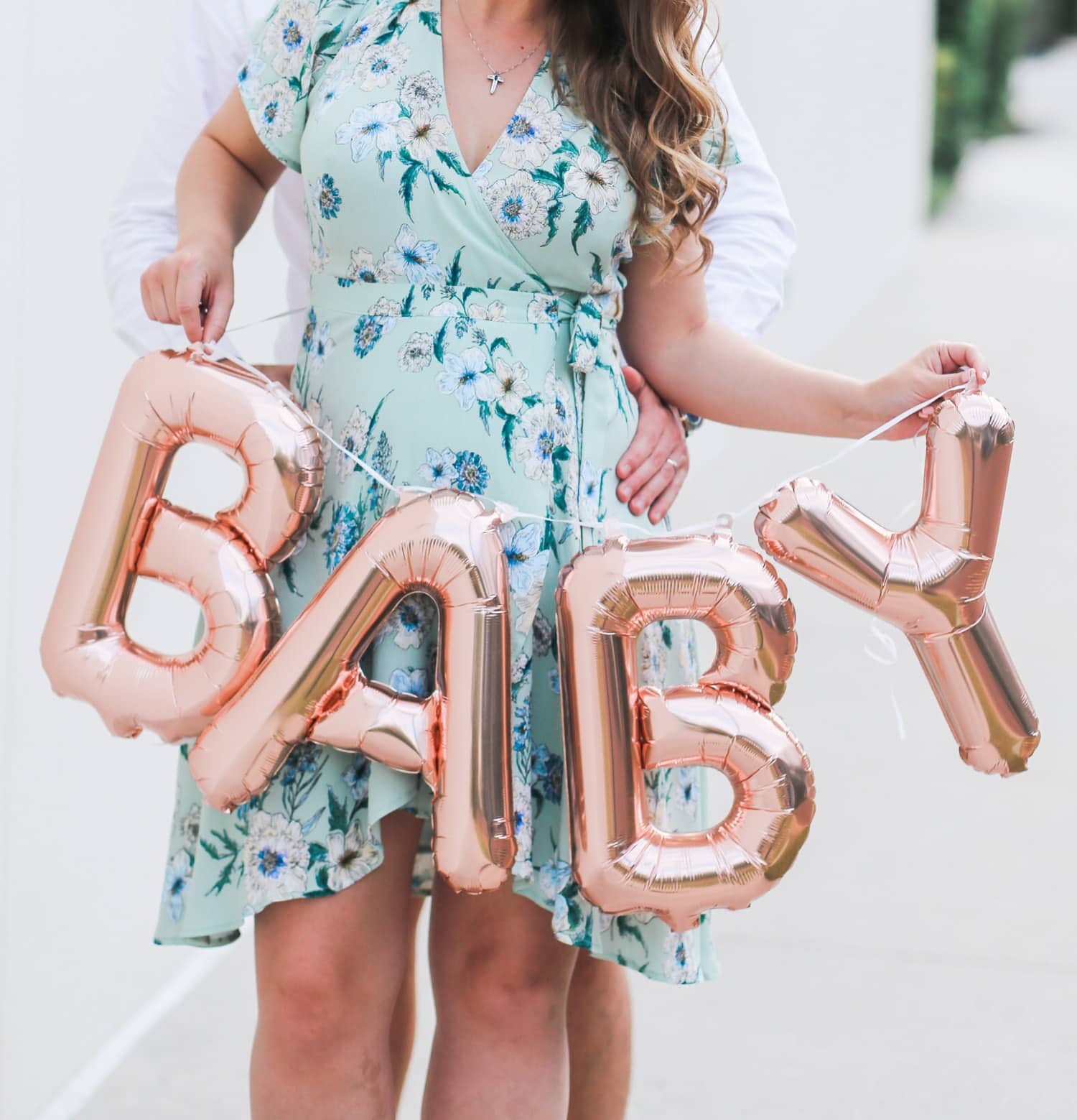 Cute pregnancy announcement photo idea | Rose gold Oh Baby balloons | ASTR pale green floral wrap dress | Flattering maternity dress | Florida beauty and fashion blogger Ashley Brooke Nicholas