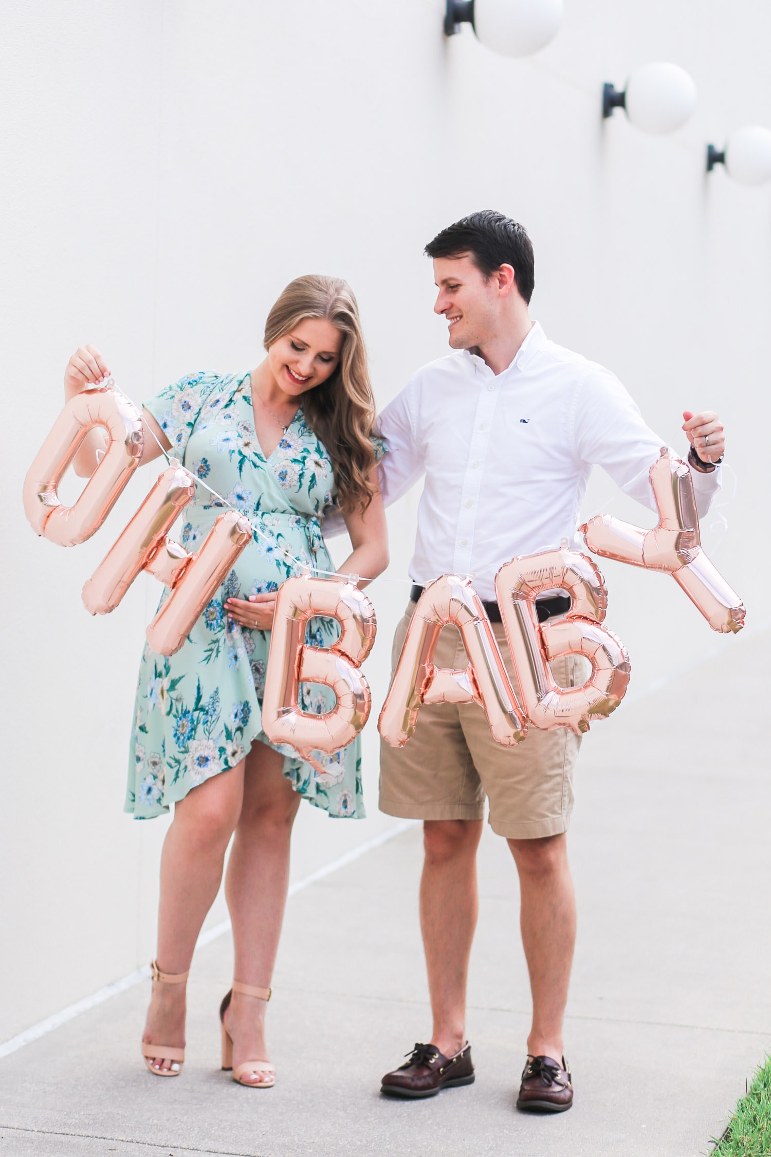 Cute pregnancy announcement photo idea | Rose gold Oh Baby balloons | ASTR pale green floral wrap dress | Flattering maternity dress | Florida beauty and fashion blogger Ashley Brooke Nicholas