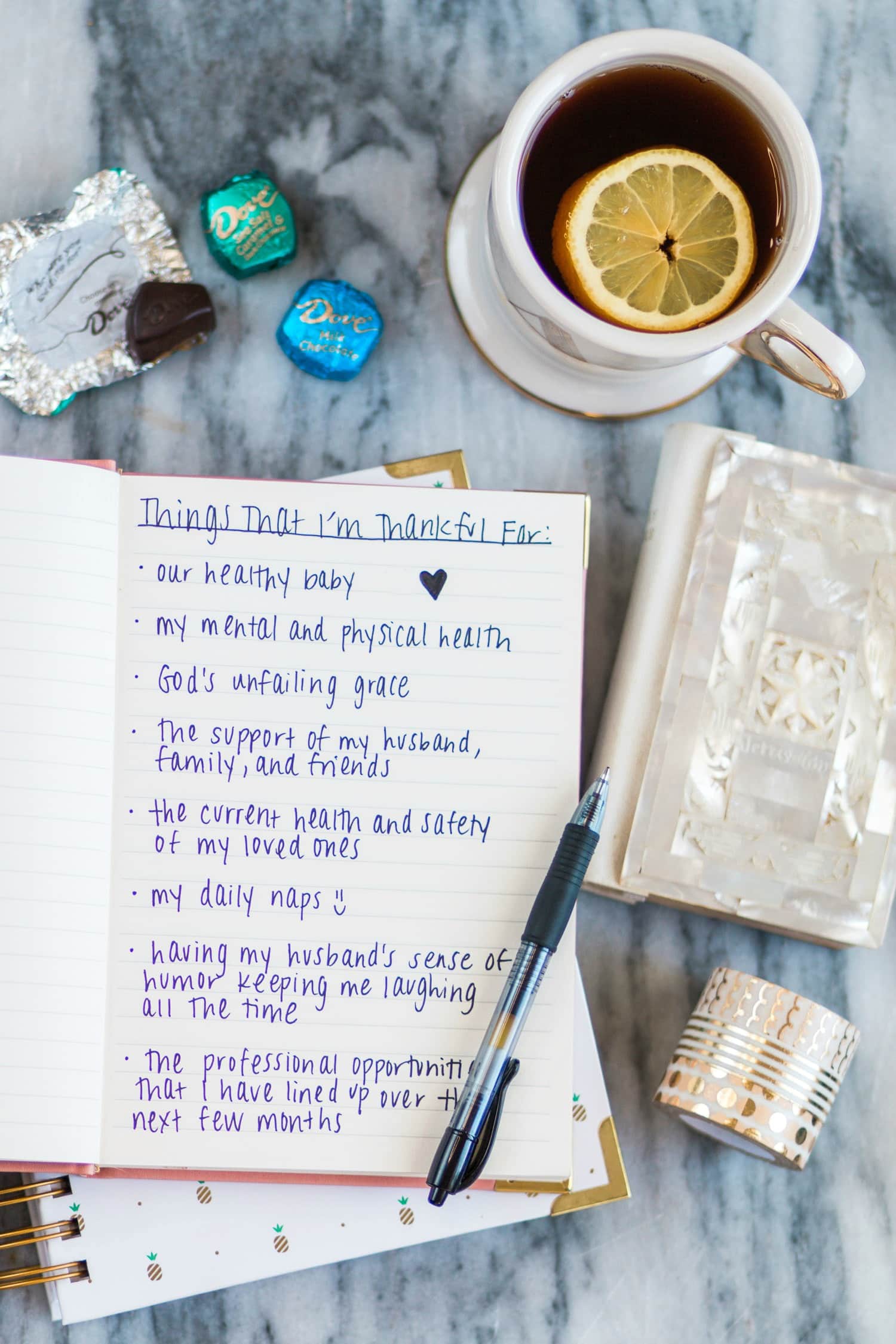 De-stress at the end of a long day by writing in a gratitude journal listing everything in your life that you're grateful for. | 10 easy ways to de-stress after a long day - including a pamper session with your favorite beauty products and creating a gratitude journal! #unwindwithdove sponsored by @DOVEChocolateUS | Dove chocolate, stress relief, how to relieve stress, how to calm down, gold candle, stress relief tips, pineapple plate, white and gold, white and gold pineapple, rhinestone bracelet, beautiful jewelry, beautiful flatlay, flatlay, red lipstick, magenta lipstick, white pink nail polish, girly inspiration | Florida lifestyle blogger Ashley Brooke Nicholas