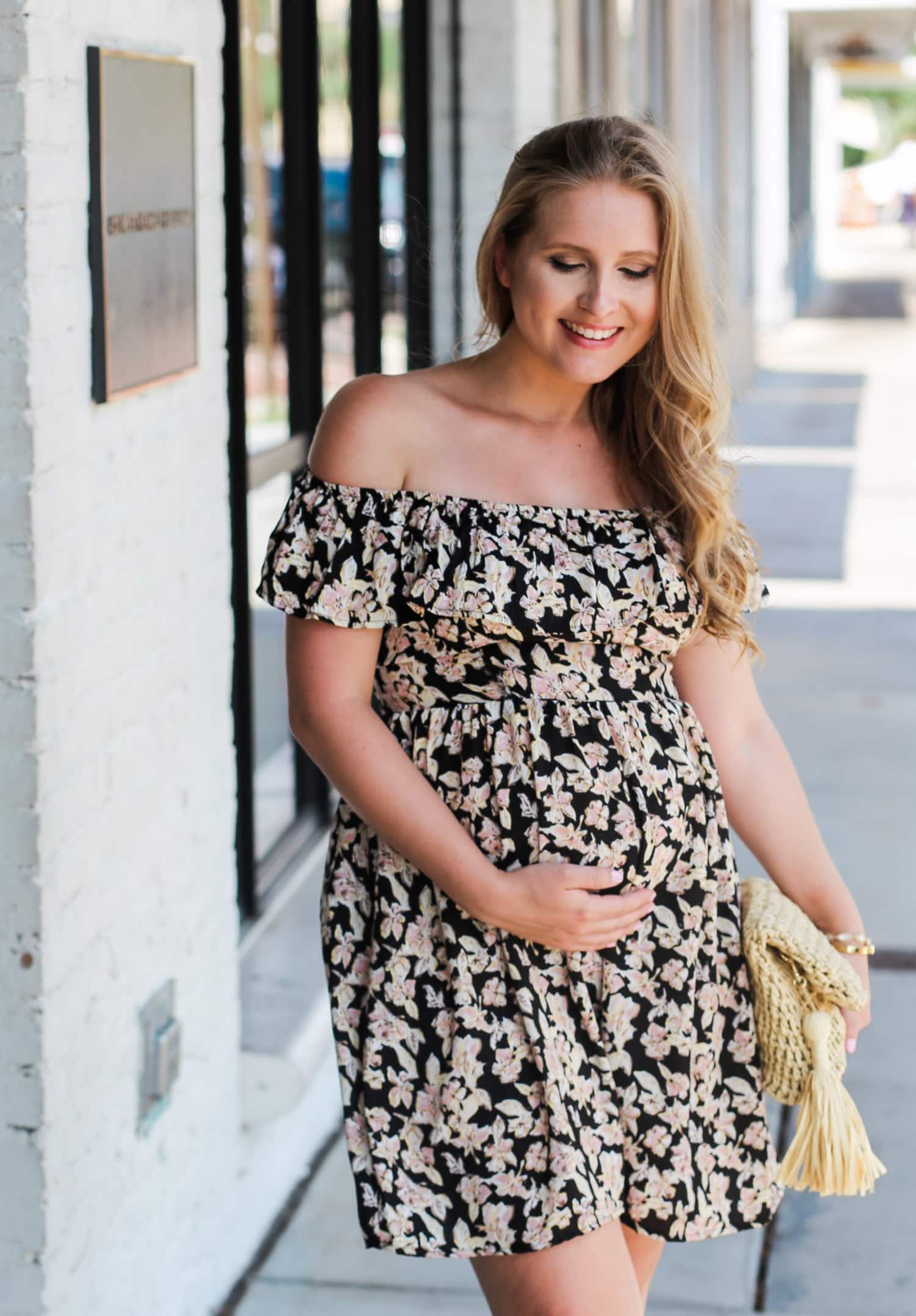 Loving this affordable floral dress for summer! It's non-maternity but still bump friendly! Can you believe this fit and flare sun dress is under $25, AND these gorgeous nude gladiator heeled sandals are also under $25? Click through this pin to see this cute summer maternity outfit idea styled by Orlando, Florida fashion blogger Ashley Brooke Nicholas! | Floral off the shoulder dress, straw clutch with tassel, raffia clutch, lace up sandals, lace up heels, cute summer heels, affordable outfit i